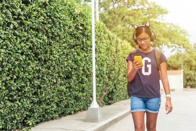 Teenager mit Kopfhörern, die beim Gehen im Park telefonieren und Musik hören