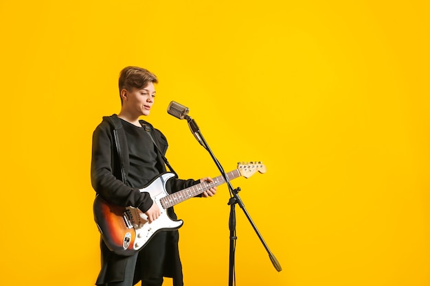 Teenager mit Mikrofon, das singt und Gitarre gegen Farbe spielt