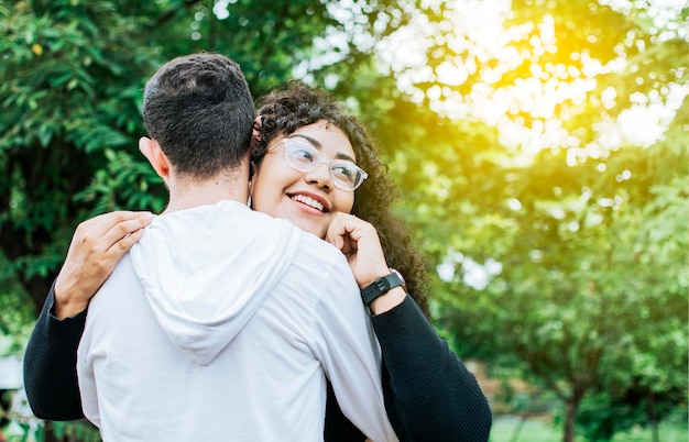 Teenager-Paar umarmt im Freien Nahaufnahme eines glücklichen Paares, das sich in der Natur umarmt Nahaufnahme eines lächelnden Teenager-Paares, das sich umarmt