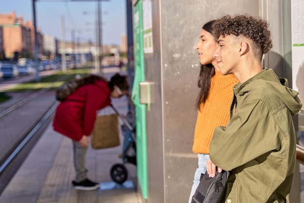 Teenager-Paar wartet auf den Zug oder Busshuttle oder Bus an einem Bahnhofskonzept für Pendler und Transport