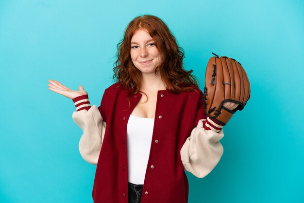 Teenager rothaariges Mädchen mit Baseballhandschuh isoliert auf blauem Hintergrund, der Zweifel hat, während er die Hände hebt