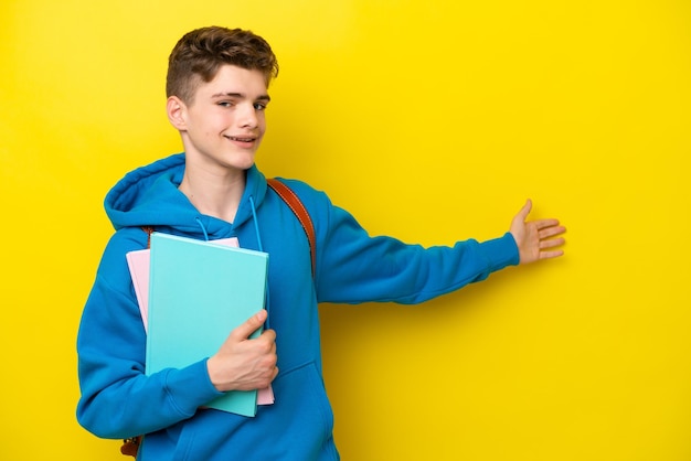 Teenager russischer Student Mann isoliert auf gelbem Hintergrund, der die Hände zur Seite streckt, um zum Kommen einzuladen