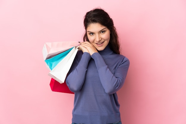 Teenager russisches Mädchen isoliert auf rosa Hintergrund mit Einkaufstüten