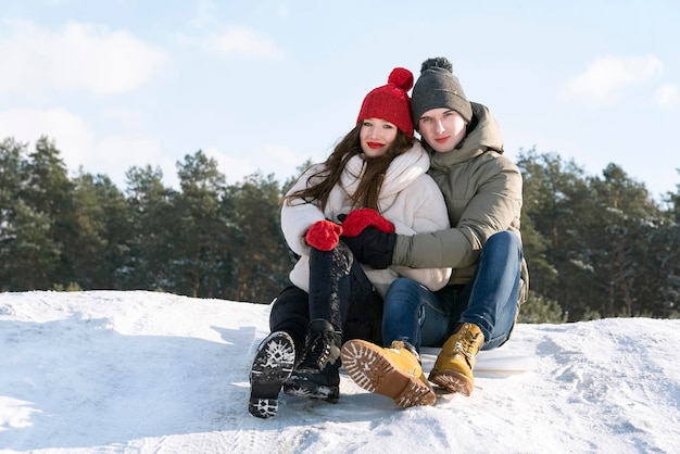 Teenager sitzen und umarmen sich vor dem Hintergrund eines Winterwaldes und blauem Himmel Datum in der Natur