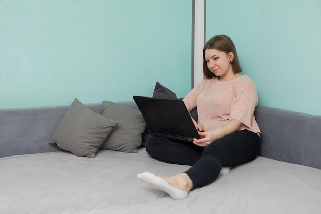 Teenager sitzt auf einem Bett vor einem Laptop mit der Absicht, online zu leben zu lernen
