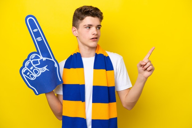 Teenager-sportfan-mann isoliert auf gelbem hintergrund, der auf eine großartige idee zeigt