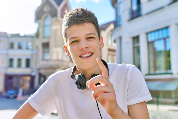 Teenager Student 16 17 Jahre alt Blick in die Kamera Guy spricht mit der Webcam und nimmt an einem sonnigen Sommertag einen Video-Blog-Stream auf der Stadtstraße auf