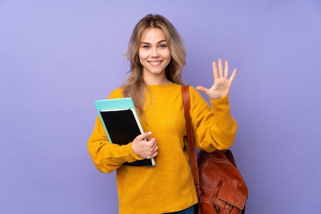 Teenager-Studentenmädchen auf lila Wand, die fünf mit den Fingern zählt