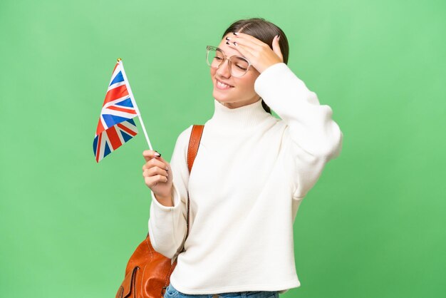 Teenager-Studentin kaukasisches Mädchen, das eine Flagge des Vereinigten Königreichs über isoliertem Hintergrund hält