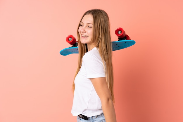 Teenager ukrainisches Skatermädchen lokalisiert auf rosa mit einem Schlittschuh mit glücklichem Ausdruck