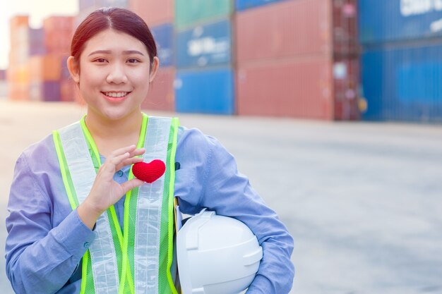 Teenagerarbeit des mädchens im frachtcontainerversandhafen, der mit herz und gutem service-verstand-konzept arbeitet.