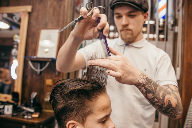 Teenagerhaarschnittfriseur im Friseursalon. Modische, stilvolle Retro-Frisur. Porträt