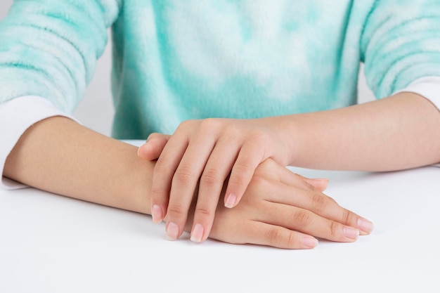 Teenagerhände, die sich auf die Handpflege auf einem Tisch beziehen