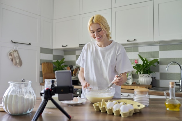 Teenagerin lernt, Pfannkuchen zu kochen, indem sie sich Videorezepte auf dem Smartphone ansieht