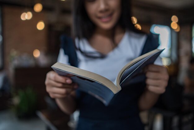 Teenagerin liest ein Buch, während sie im Restaurant steht