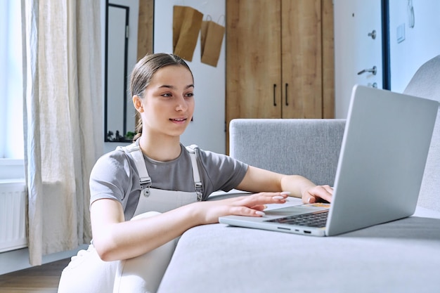 Teenagerin zu Hause auf der Couch mit Laptop