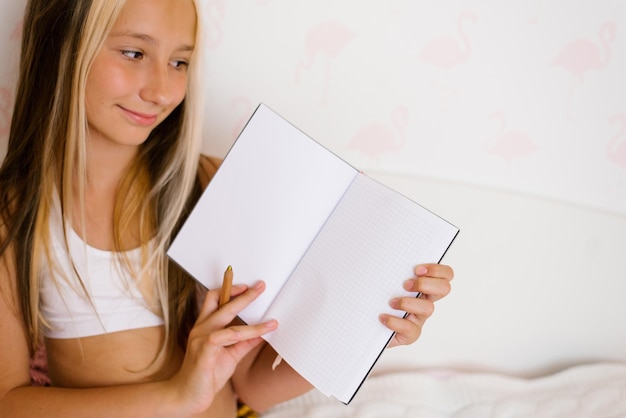 Teenagermädchen hält ein Notizbuch oder Tagebuch in ihren Händen und zeigt seinen Seiten ein Layout für den Kopierbereich