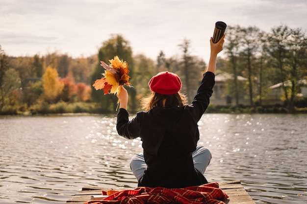 Una teengirl en un libro de lectura de boina roja sobre pontón de madera temporada de otoño