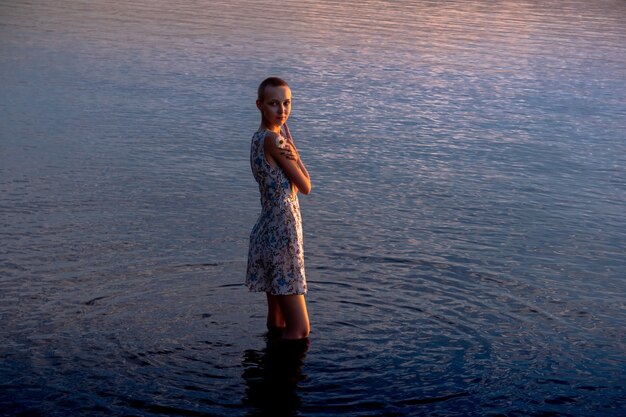 Teenie-Mädchen im Kleid am Meer versucht, ins Wasser zu gelangen