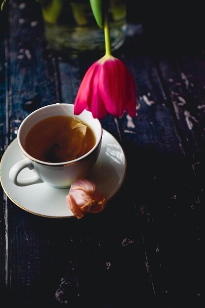 Teetasse auf hölzernem Hintergrund mit Frühlingstulpen und weißem Blatt