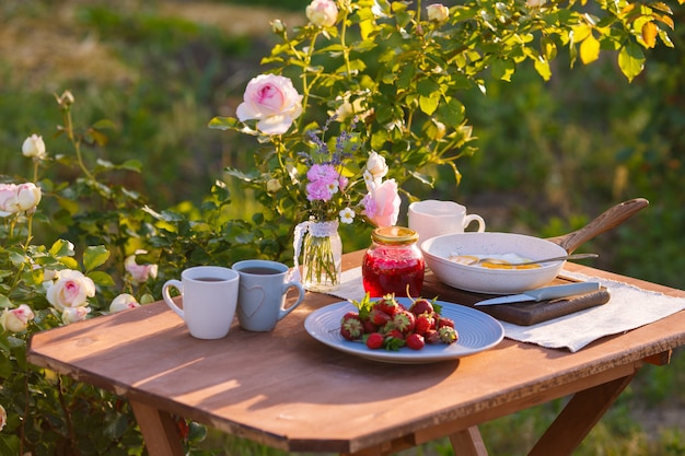 Foto teetassen mit rosa rosen auf einem holztisch am morgen