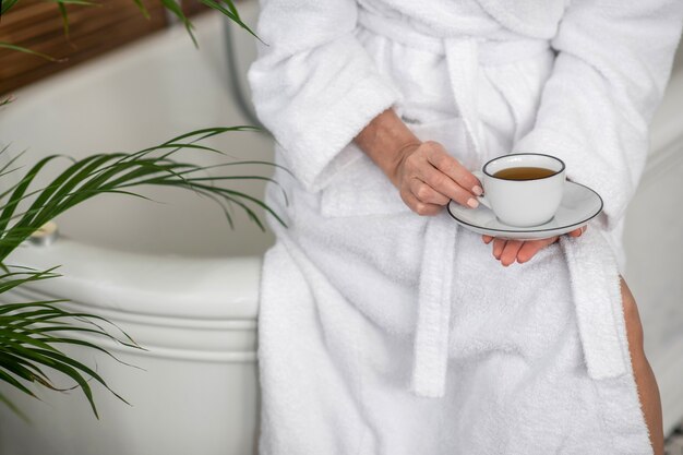 Teezeit. Frau in einem weißen Gewand, das eine Tasse mit Tee hält