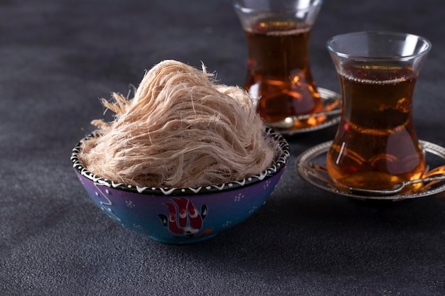 Teezeremonie mit türkischer Zuckerwatte Pismaniye auf dunklem Hintergrund. Nahansicht