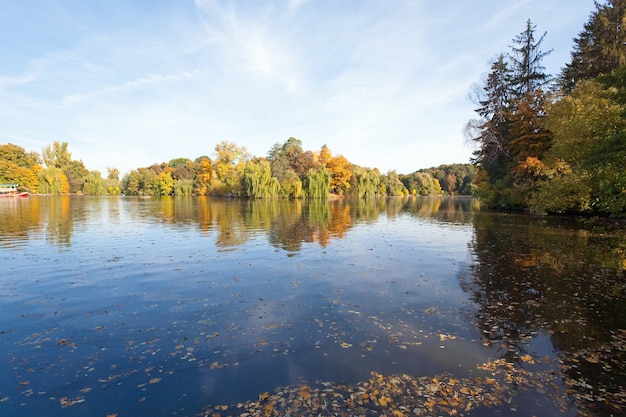 Teichwasseroberfläche mit Reflexion der bunten Bäume im Herbstpark