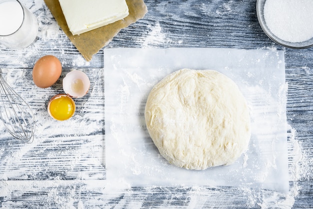 Teig, der Rezeptbrot, Pizza oder Kuchenmischmittel mischt, lag flach auf Küchentischhintergrund. Arbeiten mit Butter, Milch, Mehl, Eiern, Zucker oder Backwaren.