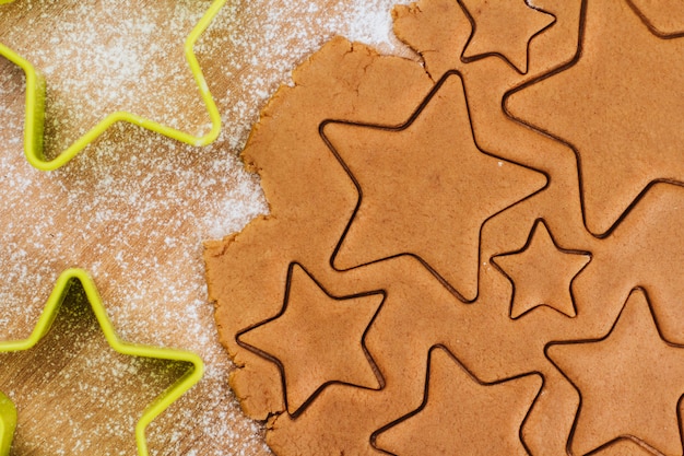 Teig für Lebkuchen auf einem Tisch mit Mehl bestreut. Kekse in Form von Sternen schneiden.