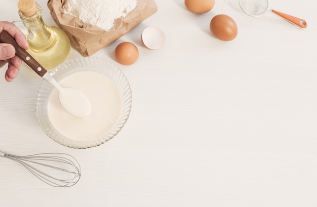 Teig in Glasplatte und Produkte für seine Zubereitung auf weißem Hintergrund