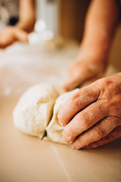 Foto teig machen durch weibliche seniorenhände in der bäckerei. food-konzept.