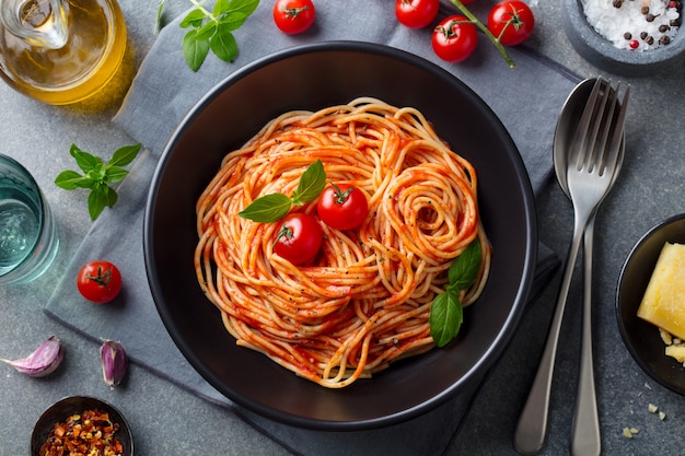 Teigwaren, Spaghettis mit Tomatensauce in der schwarzen Schüssel. Ansicht von oben.