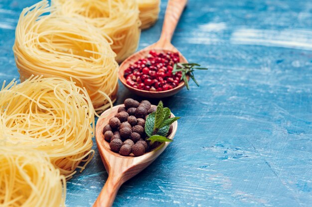 Teigwarenspaghettis, Gemüse und Gewürze, auf Holztisch