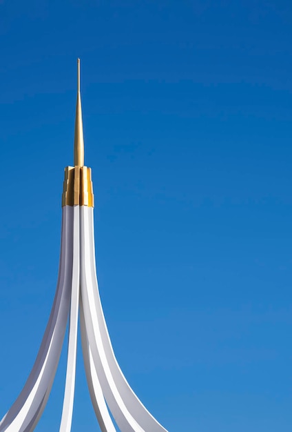 Teil des Kurvenlinienmusters der weißen und goldenen Turmspitze auf dem Gebäude gegen den klaren blauen Himmel