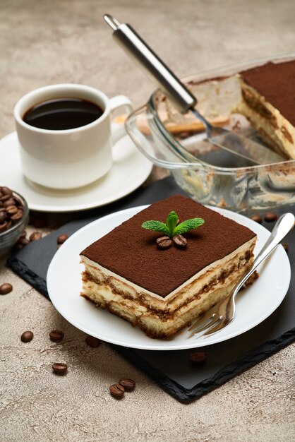 Teil des traditionellen italienischen Tiramisu-Desserts und der Mokka-Kaffeemaschine auf grauem Betontisch