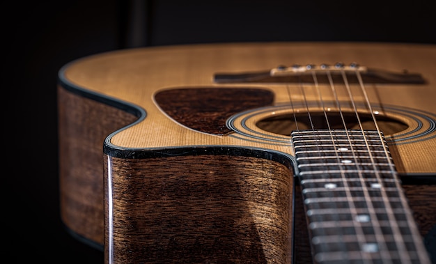 Teil einer Akustikgitarre, Gitarrengriffbrett mit Saiten auf schwarzem Hintergrund.