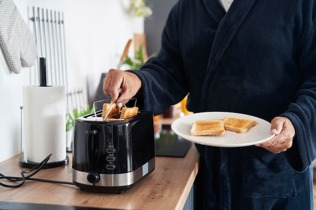 Teil eines älteren kaukasischen Mannes, der zu Hause Frühstück zubereitet