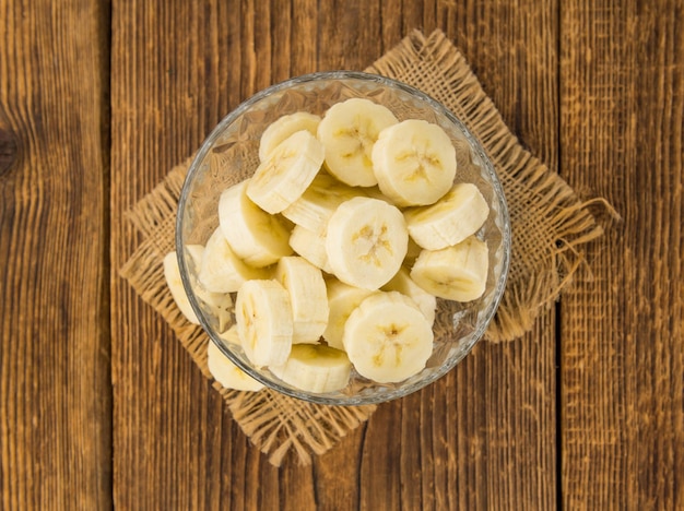 Teil geschnittene Bananen auf selektivem Fokus des hölzernen Hintergrundes Beschneidungspfad eingeschlossen