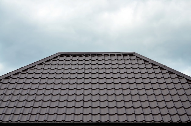 Tejas o tejas de tejado de Brown en casa como imagen de fondo. Nuevo patrón de textura de material de techado de estilo clásico marrón superpuesto en una casa