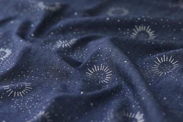 Tejido azul y blanco ondulado con imagen de sol de primer plano de textil azul con adorno de sol blanco