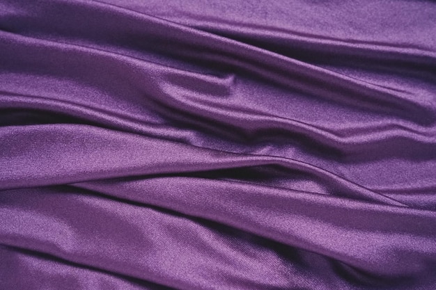 Tejido de velour similar a los textiles de seda en pliegues y hermosas ondas en tonos púrpura rosa magenta