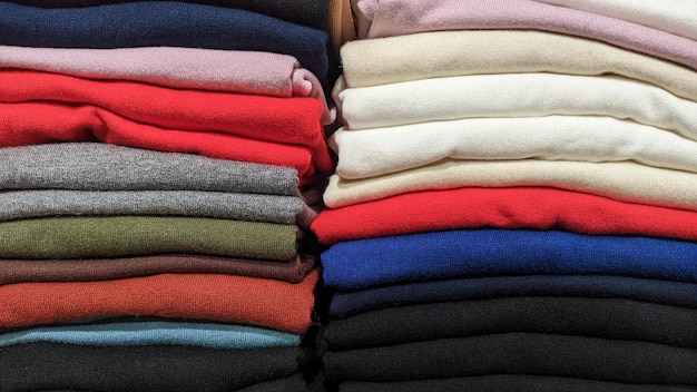Tejidos de diferentes colores apilados uno encima del otro en una pila vendiendo textiles en una tienda