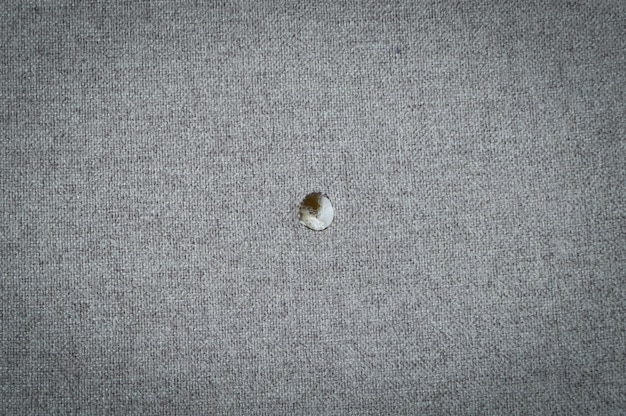 Tela de algodón con un agujero de un cigarrillo.