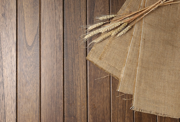 Foto tela de arpillera en la mesa de madera un poco de trigo