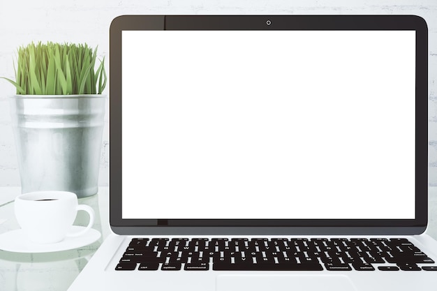 Tela branca em branco do laptop com xícara de café e balde com grama simulada
