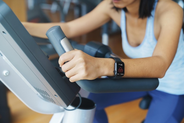 Tela do aplicativo Pulse no smartwatch nas mãos de uma mulher se exercitando em um clube esportivo