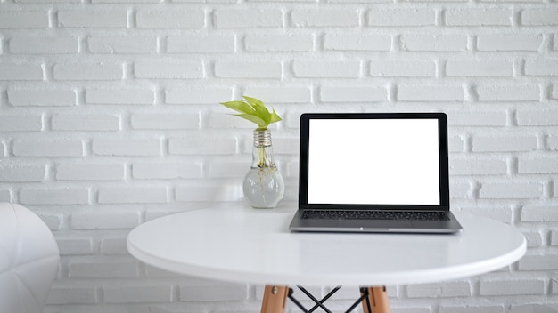 Tela do laptop de maquete em branco vazia com um vaso de lâmpada na mesa moderna branca no café