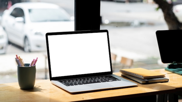 Tela em branco do laptop na mesa de madeira na cafeteria.