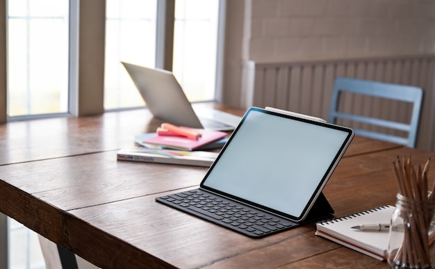Tela em branco do tablet Digital de maquete e equipamento de escritório na mesa de madeira.